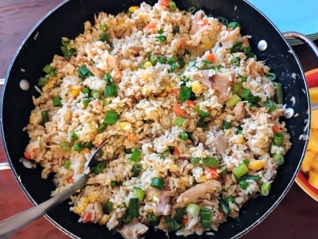 Overhead view of a skillet filled with a freshly cooked chicken fried rice recipe.